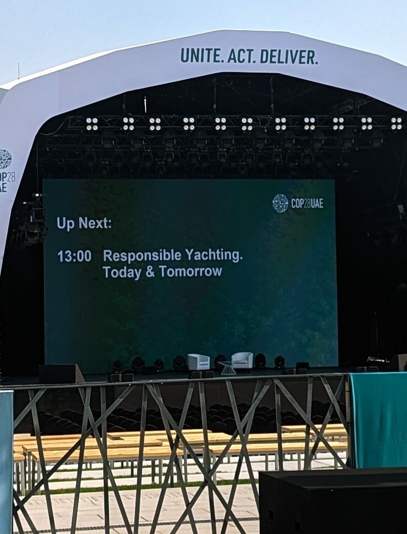Photo of a panel during the climate conference. It announces the upcoming panel on yachting. It's placed in the heat of the day 