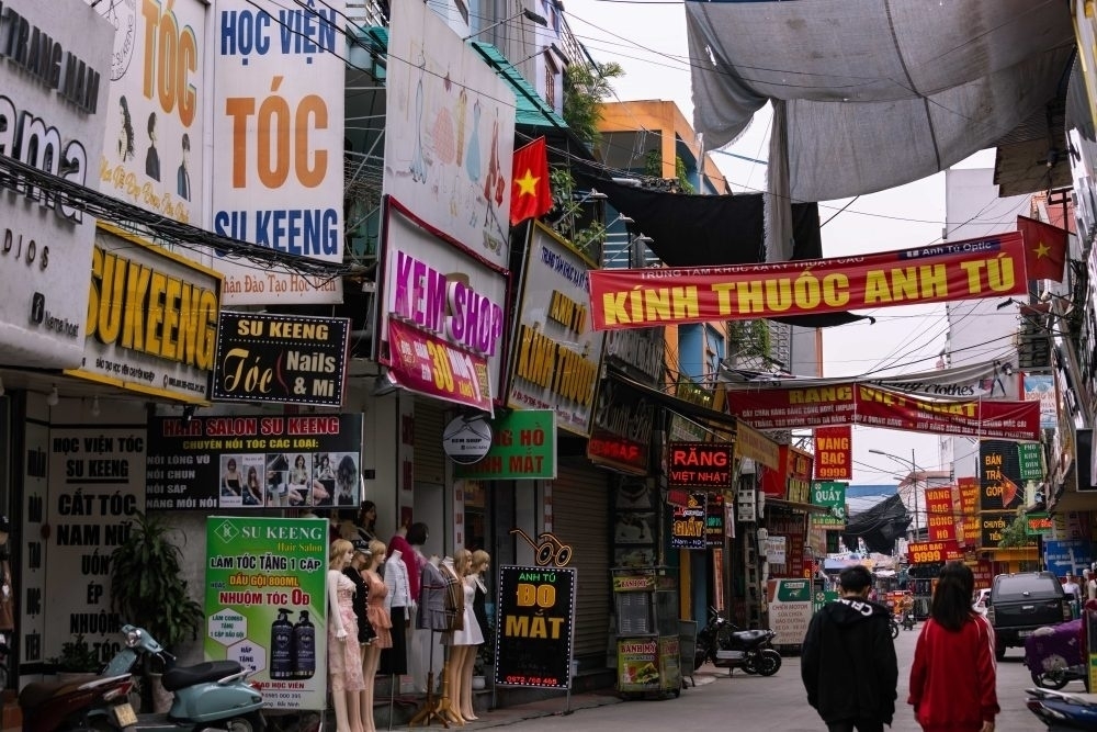 Image from the article: you see a street busy with ads in Vietnamese. The original text: The streets around the Samsung complex in Bac Ninh are lined with salons offering beautician courses.