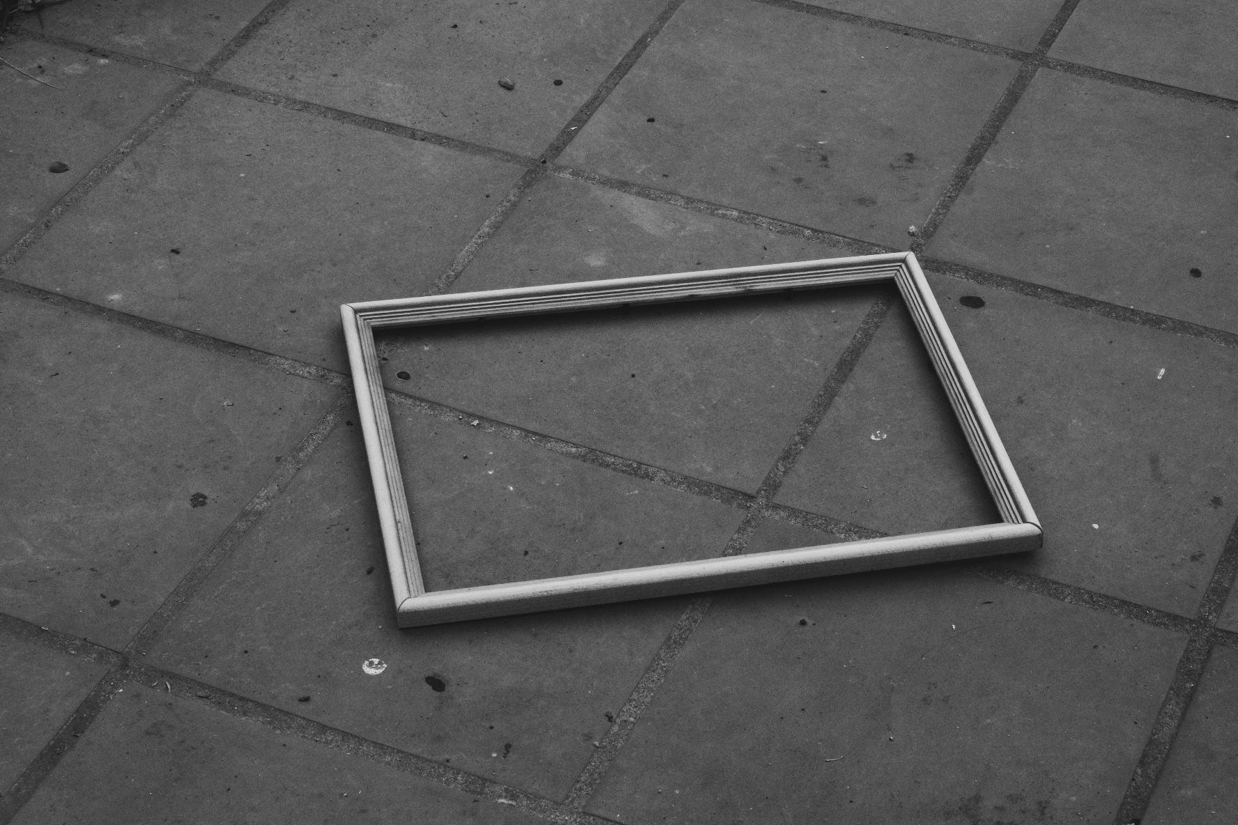 B/w Photo of an empty frame on the floor. Piles below. A bit of dust. And the frame had a slight and strange glow to it